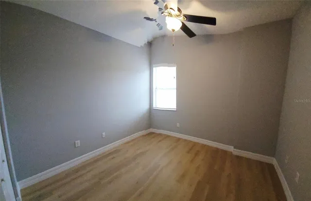 an empty room with windows and fan