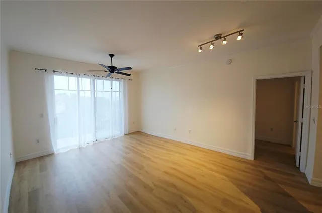 a view of an empty room with wooden floor and a window