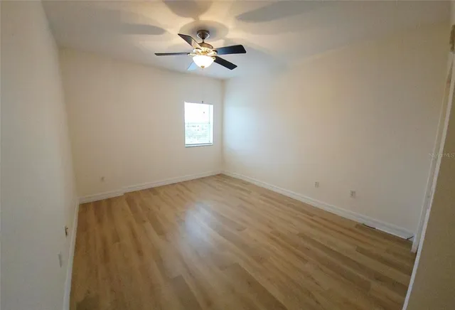 an empty room with a chandelier fan and windows