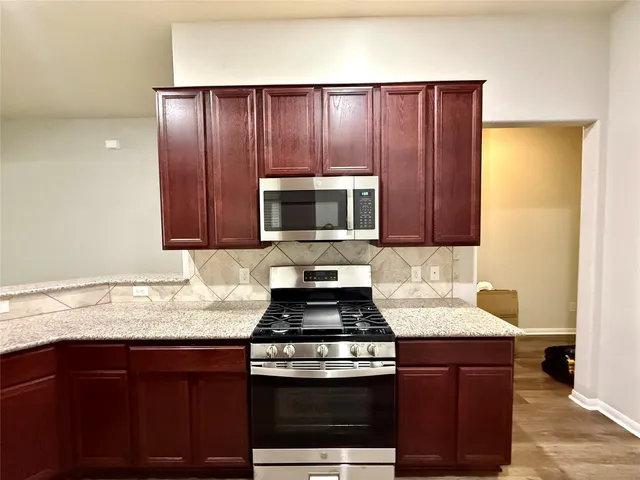 a kitchen with granite countertop wooden cabinets and a stove top oven