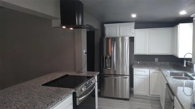 a kitchen with stainless steel appliances granite countertop a refrigerator a sink and a stove