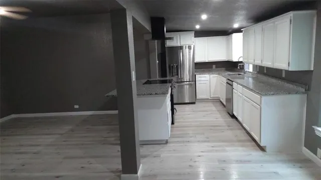 a kitchen with kitchen island granite countertop a refrigerator a sink and white cabinets