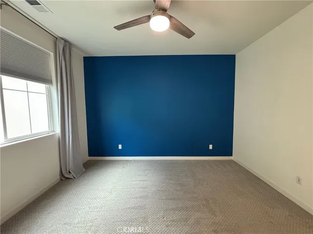 an empty room with windows and fan