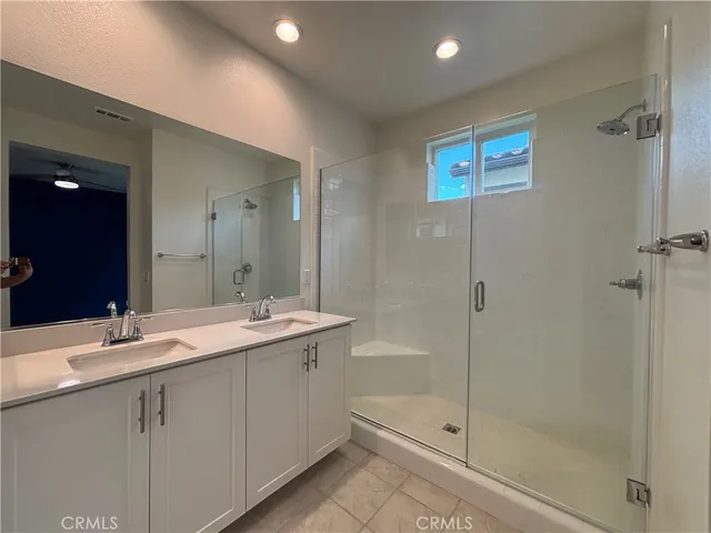 a bathroom with a double vanity sink mirror and shower