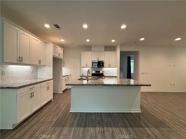 a kitchen with stainless steel appliances granite countertop a stove a sink and a refrigerator