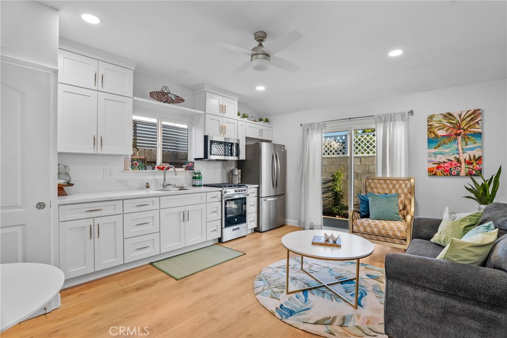a living room with stainless steel appliances furniture and a kitchen view