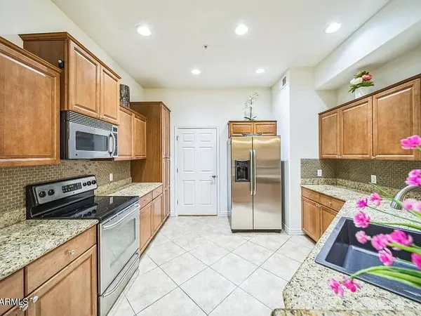 a kitchen with granite countertop a refrigerator stove top oven and sink