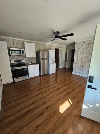 a view of a kitchen with wooden floor and electronic appliances