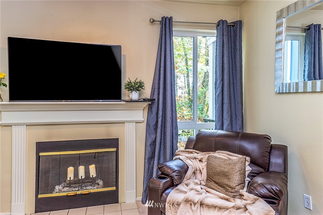 3918 243rd Place Southeast, Unit F304 Bothell, WA 98021 - Photo 16 of 25 a living room with a fireplace and a flat screen tv