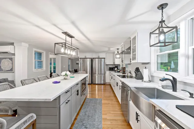 a large white kitchen with kitchen island a stove a sink dishwasher and white cabinets with wooden floor