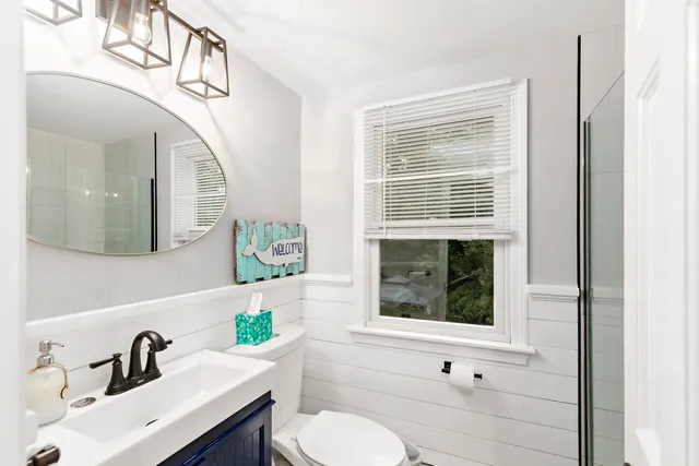 a bathroom with a sink a mirror a toilet and a window