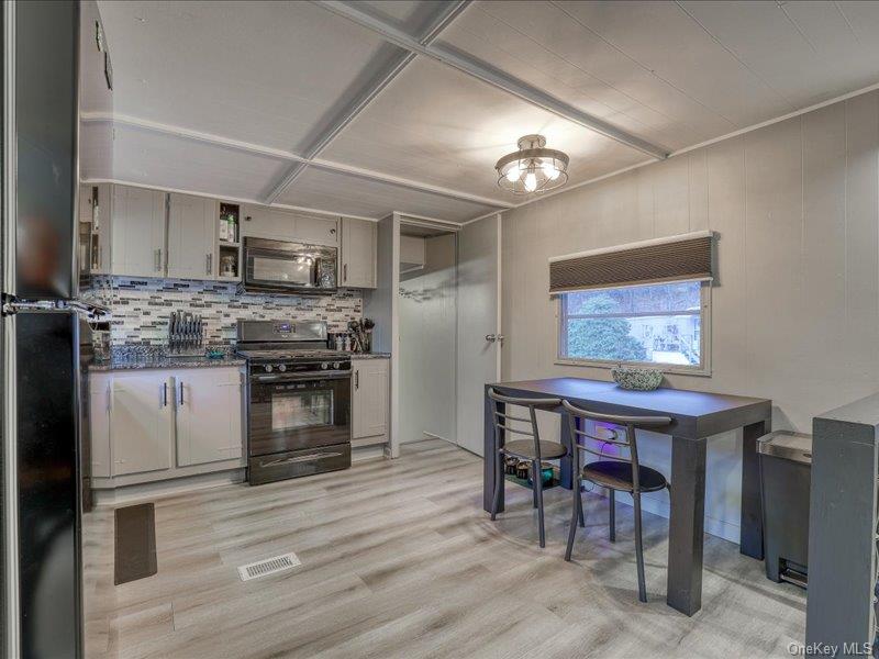 a kitchen with stainless steel appliances granite countertop a stove top oven a sink dishwasher a dining table and chairs with wooden floor
