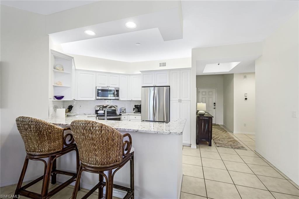 470 Launch Circle, Unit V301 Naples, FL 34108 - Photo 10 of 39 a kitchen with stainless steel appliances granite countertop a dining table chairs and a refrigerator