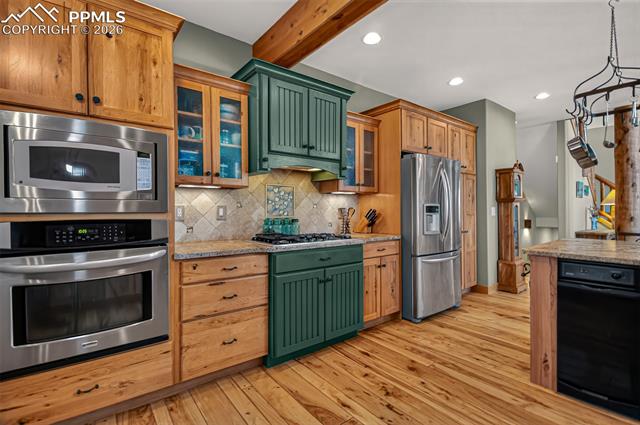 255 Summit Road Manitou Springs, CO 80829 - Photo 14 of 48 Open concept kitchen with leathered granite countertops, pullout pantry shelves, custom knotty hickory cabinetry, window seat with storage, knotty pecan flooring, breakfast bar seating and custom painted aspen tiles!