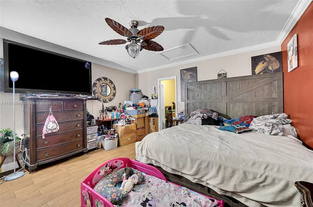 a bedroom with a bed a flat screen tv and a chandelier