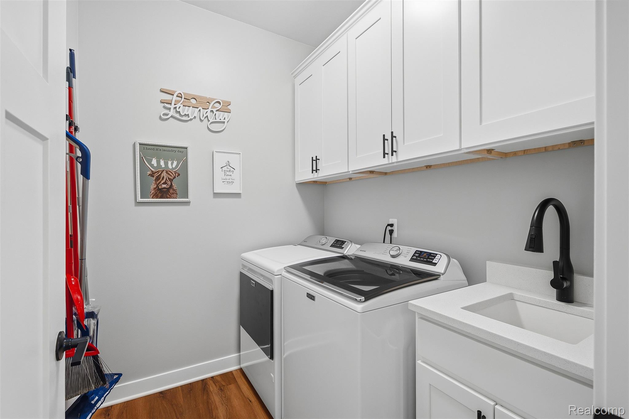 9087 Copper Ridge Drive Davison, MI 48423 - Photo 26 of 46 Dedicated laundry room featuring wood-finish flooring, white cabinetry with black hardware, a utility sink with a matte black faucet, and light-colored countertops