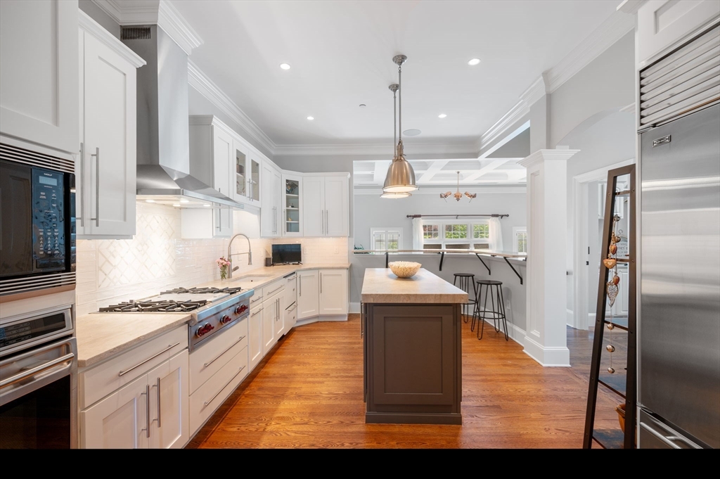 221 Victory Road, Unit 221 Quincy, MA 02171 - Photo 7 of 34 a kitchen with stainless steel appliances granite countertop a stove top oven a refrigerator and white cabinets with wooden floors