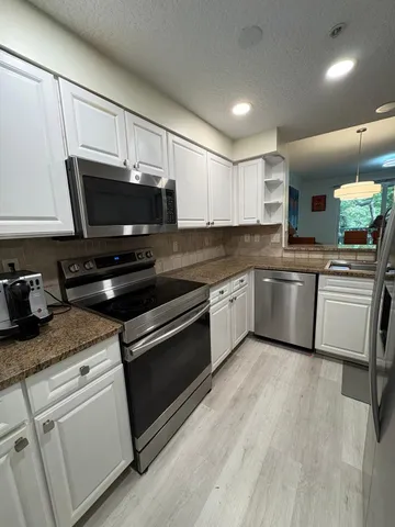 a kitchen with granite countertop a sink stainless steel appliances and white cabinets
