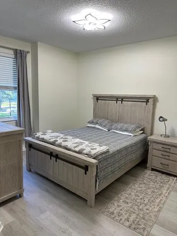 a bed sitting in a spacious bedroom next to a window