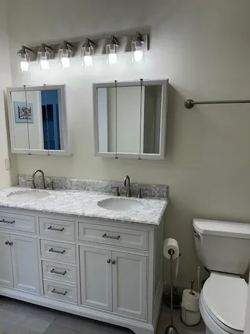 a bathroom with a granite countertop sink and a toilet