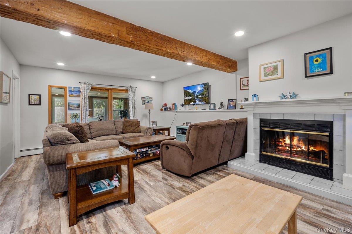 10 Richard Road Mahopac, NY 10541 - Photo 18 of 33 Living area with beamed ceiling, recessed lighting, light wood-style flooring, a tiled fireplace, and a baseboard radiator