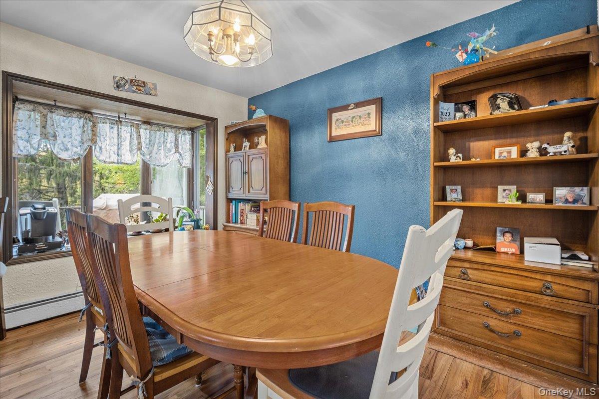 10 Richard Road Mahopac, NY 10541 - Photo 5 of 33 Dining room featuring a textured wall, light wood-style floors, a baseboard radiator, and a chandelier