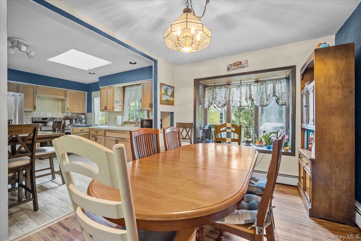 10 Richard Road Mahopac, NY 10541 - Photo 6 of 33 Dining room featuring light wood finished floors, a chandelier, a baseboard radiator, and a skylight
