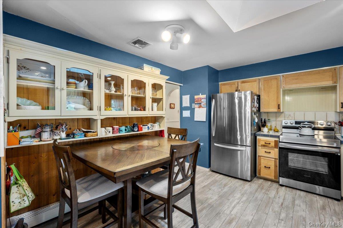 10 Richard Road Mahopac, NY 10541 - Photo 8 of 33 Kitchen featuring stainless steel appliances, glass insert cabinets, light wood-type flooring, decorative backsplash, and light countertops