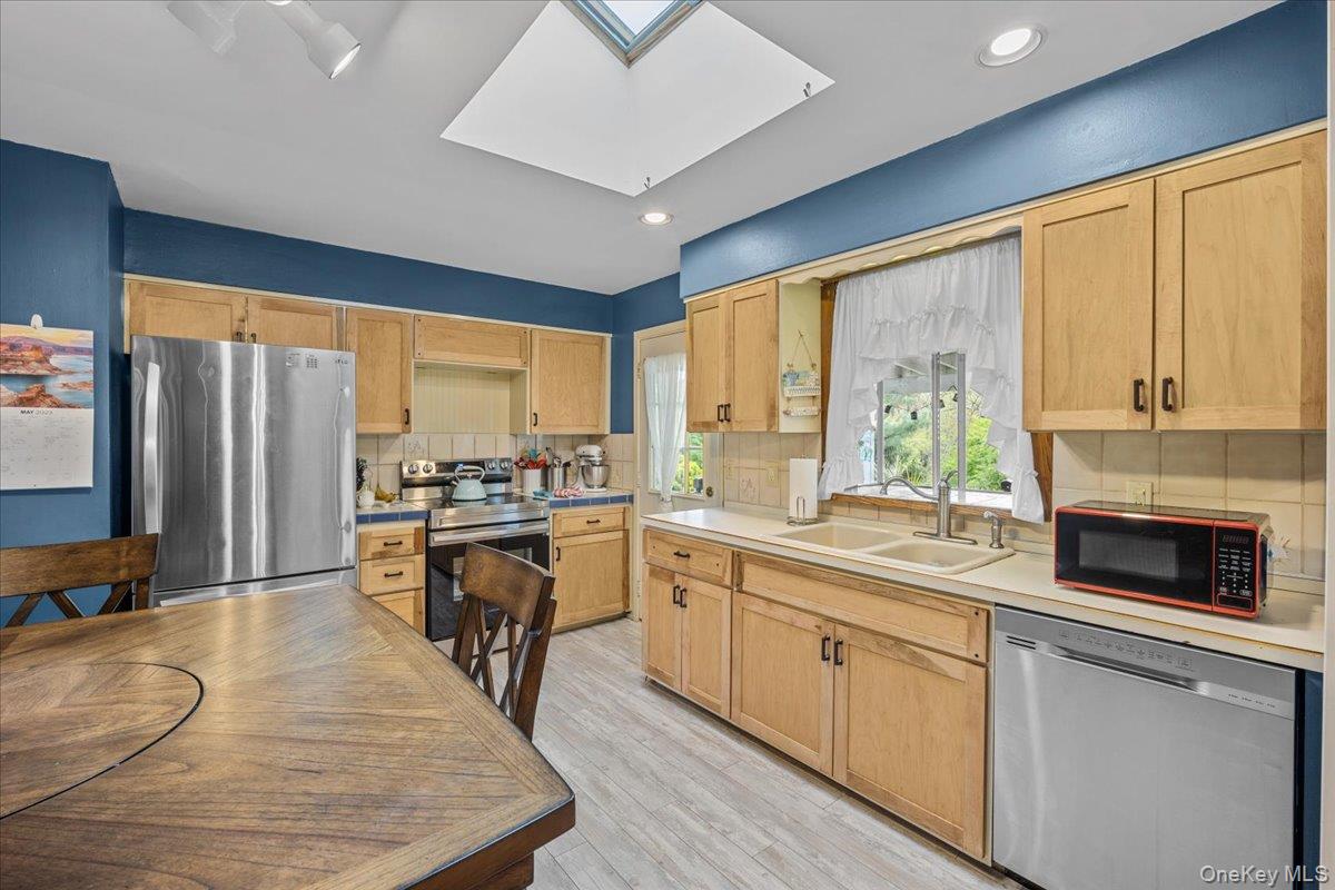 10 Richard Road Mahopac, NY 10541 - Photo 9 of 33 Kitchen featuring light countertops, a skylight, backsplash, stainless steel appliances, and light brown cabinets