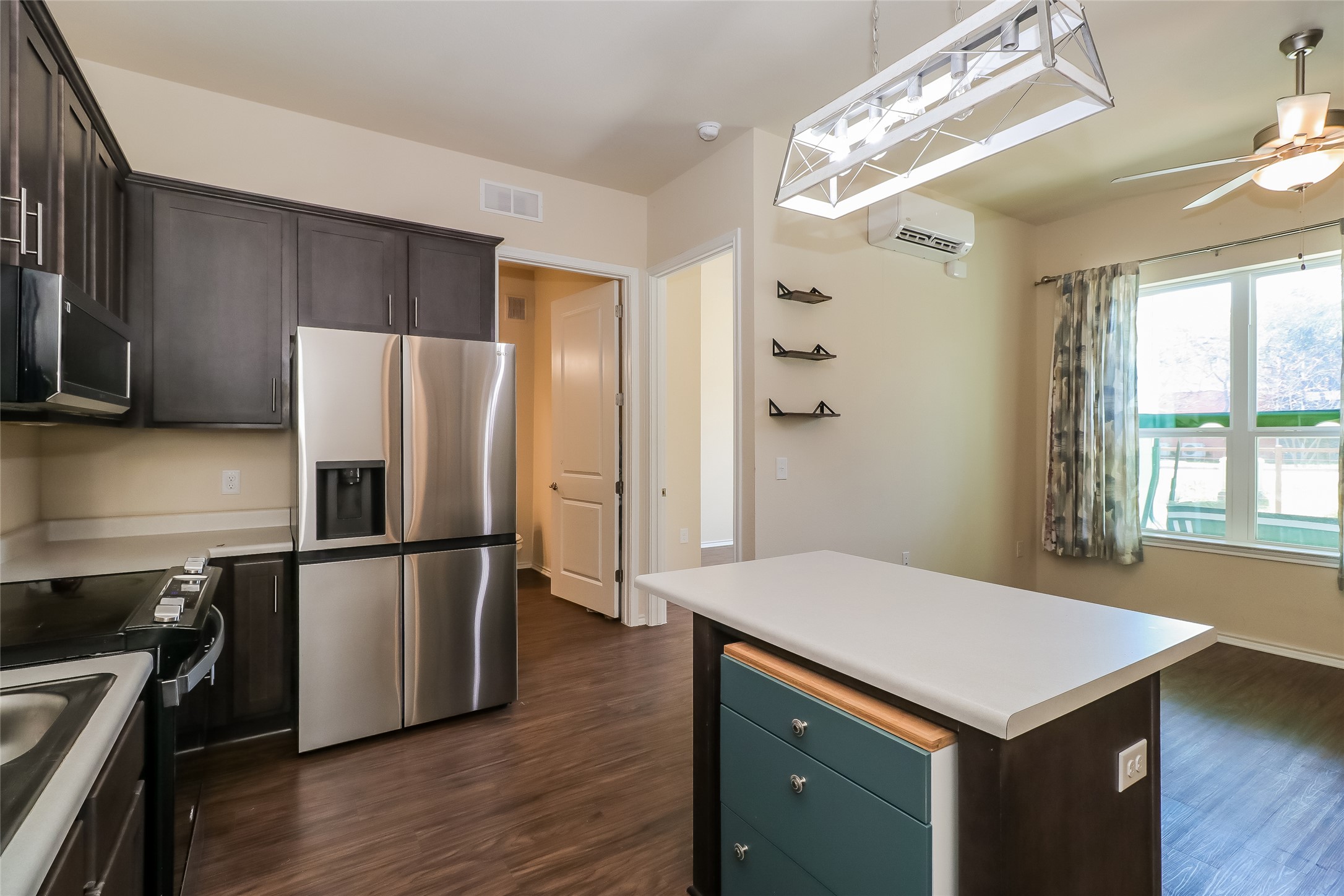 8601 West Gate Boulevard, Unit 7101 Austin, TX 78745 - Photo 9 of 16 Kitchen featuring stainless steel refrigerator with ice dispenser, dark wood finish cabinetry, light countertops, decorative light fixtures, and a ceiling fan