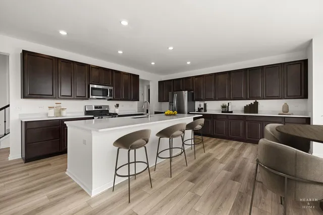 a kitchen with kitchen island granite countertop wooden floors a refrigerator and cabinets