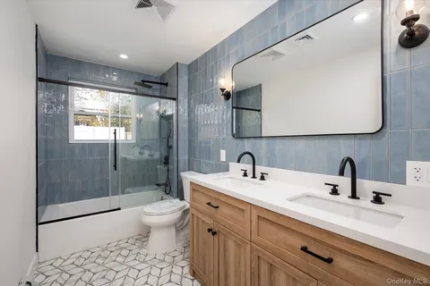 a bathroom with a double vanity sink toilet mirror and shower