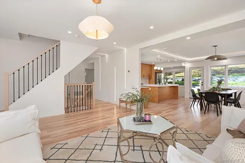 a living room with couches and dining table with wooden floor