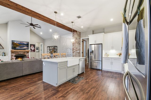 a kitchen with stainless steel appliances granite countertop a sink a stove a refrigerator cabinets and chairs