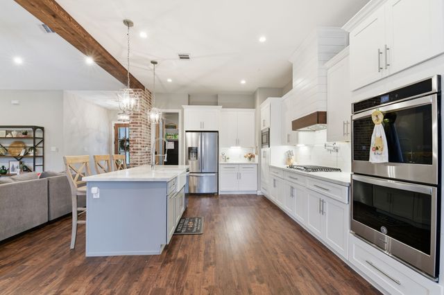 a large white kitchen with a refrigerator a stove top oven a sink and cabinets