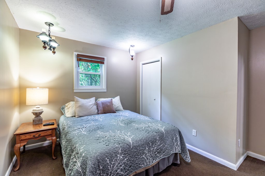 411 Piney Acres Road Blue Ridge, GA 30513 - Photo 27 of 72 a bedroom with a bed and lamp