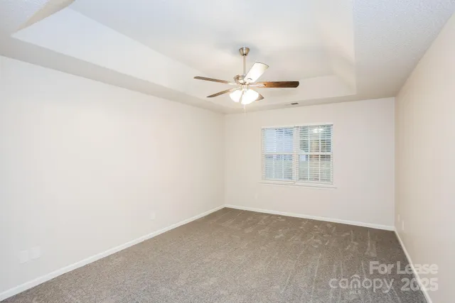 an empty room with a chandelier fan and windows