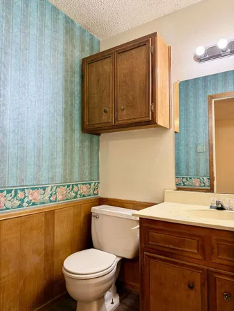a bathroom with a granite countertop toilet sink and mirror