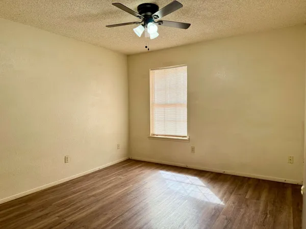 an empty room with a window and a ceiling fan