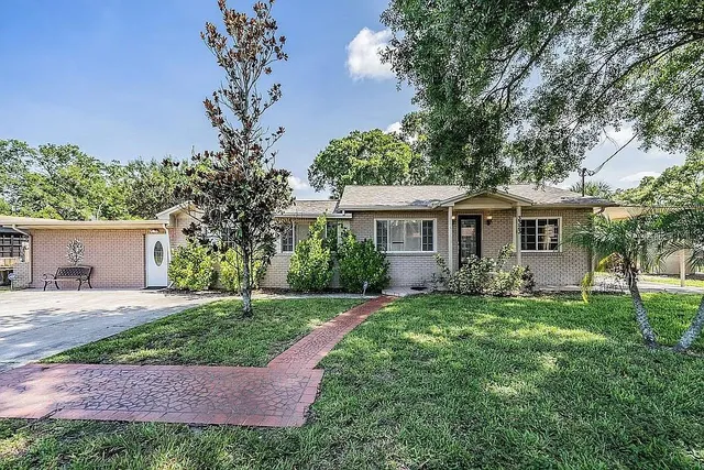 a view of a house with a yard and a large tree