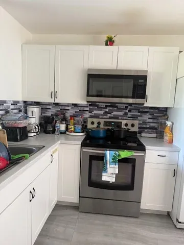 a kitchen with stainless steel appliances a stove a white cabinets and a sink