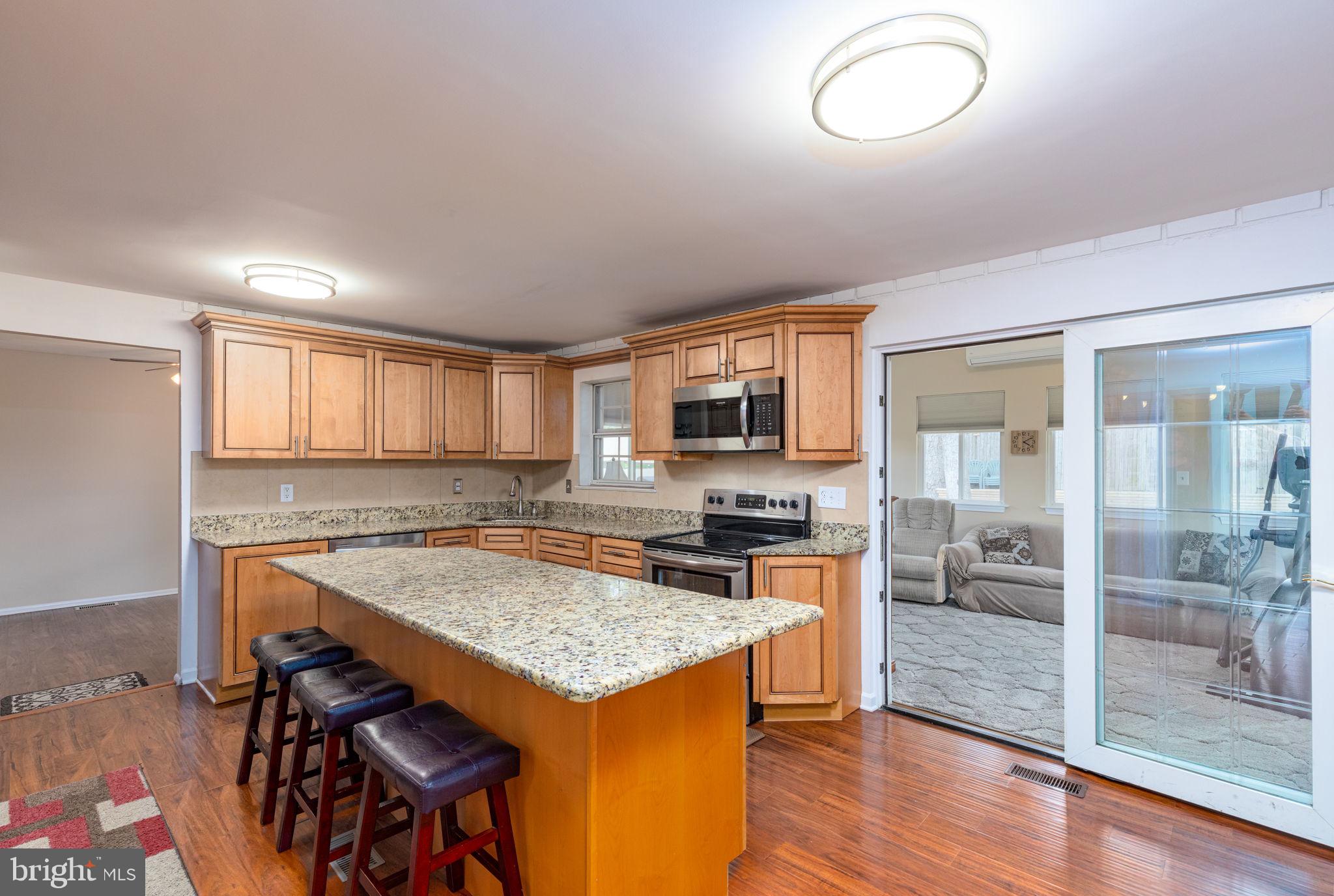 9021 Moonstone Road Nottingham, MD 21236 - Photo 9 of 36 a kitchen with a stove a refrigerator a sink and a dining table with wooden floor