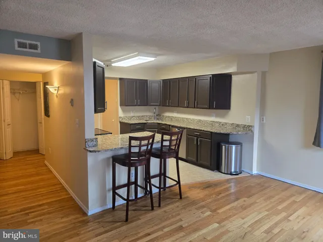 a open kitchen with granite countertop a stove and a wooden floor