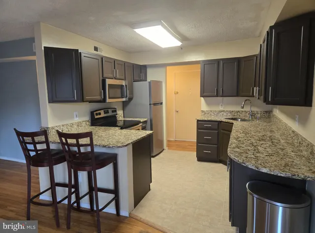 a kitchen with granite countertop a stove a sink and a refrigerator
