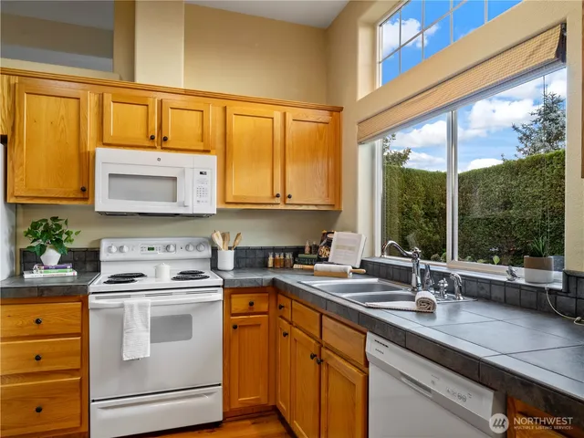 a kitchen with stainless steel appliances a sink a stove and white cabinets next to a window
