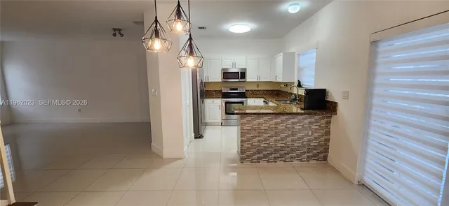 a kitchen with granite countertop a refrigerator and a stove top oven
