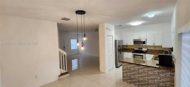 a kitchen with stainless steel appliances granite countertop a refrigerator and a stove top oven