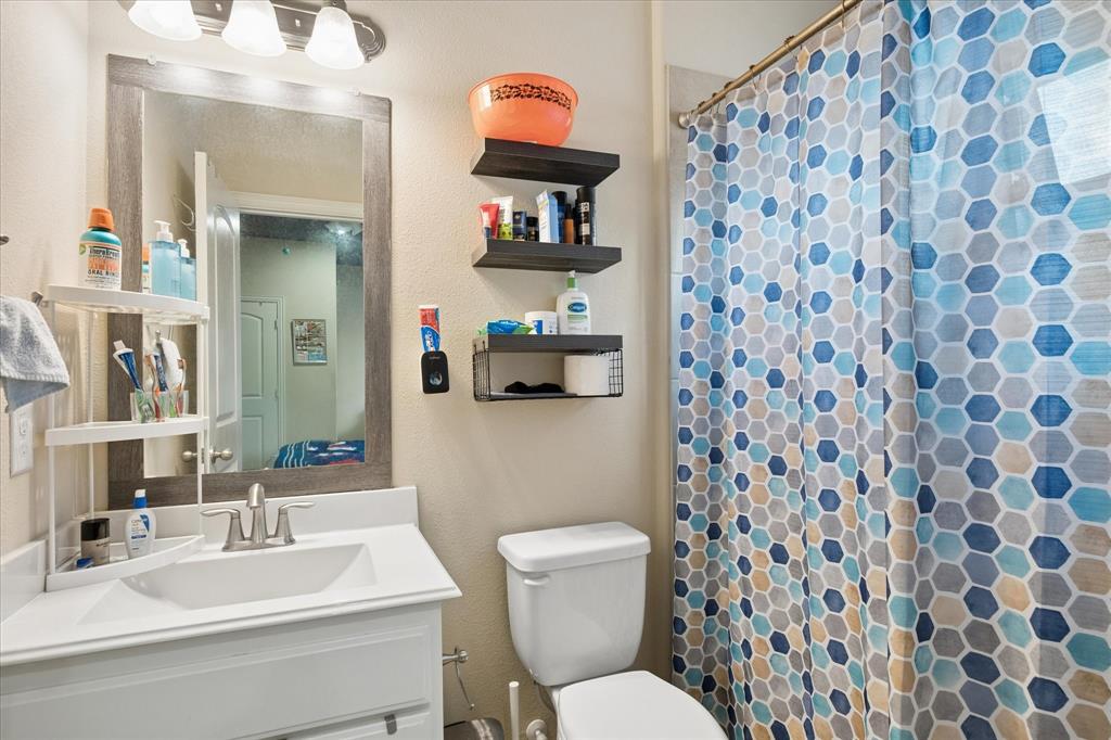 8268 Kara Creek Road Frisco, TX 75036 - Photo 23 of 31 Bathroom featuring a single vanity with a white countertop and integrated sink, a rectangular framed mirror, and a three-light vanity fixture
