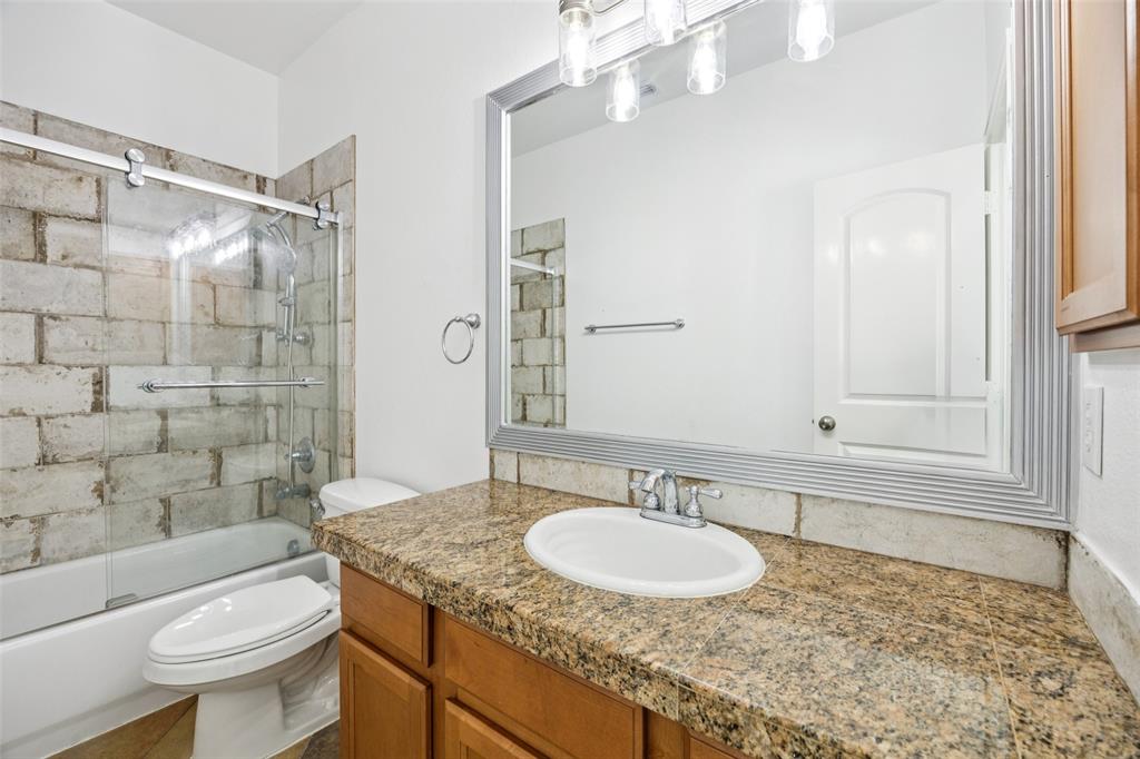 1503 Biltmore Lane Irving, TX 75063 - Photo 13 of 34 a bathroom with a granite countertop sink a toilet a mirror and shower