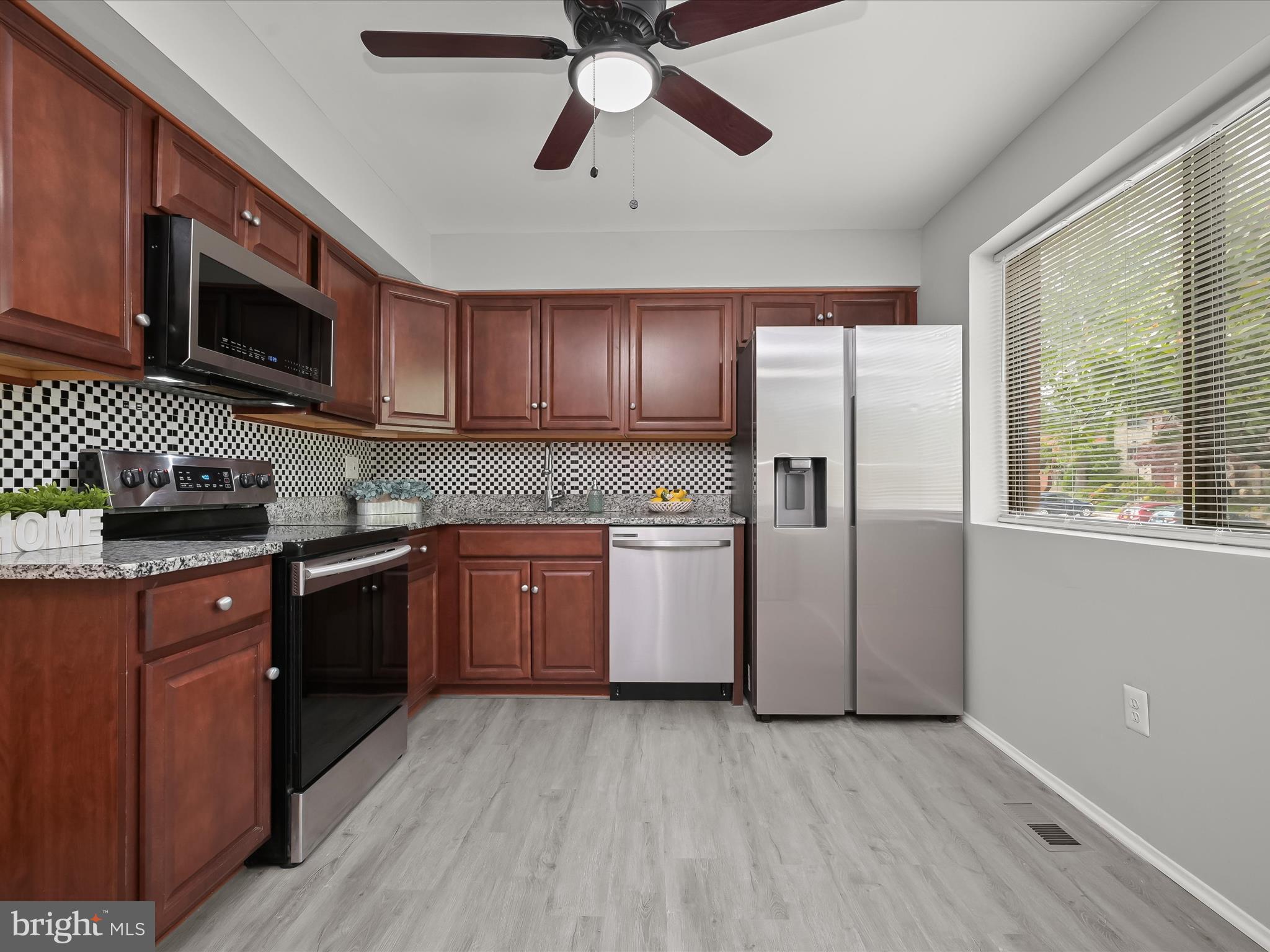 7106 Winter Rose Path Columbia, MD 21045 - Photo 2 of 50 a kitchen with stainless steel appliances granite countertop a refrigerator a sink dishwasher a stove with wooden cabinets and floor
